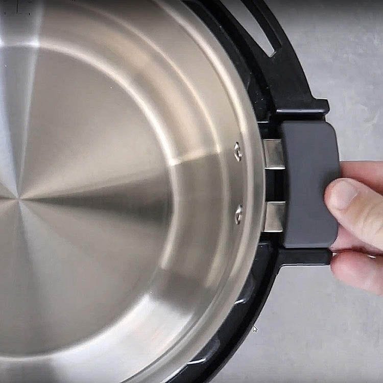 Stainless steel pot interior with a hand holding the pot handle, showcasing high-quality cookware for healthy cooking and kitchen enhancement.